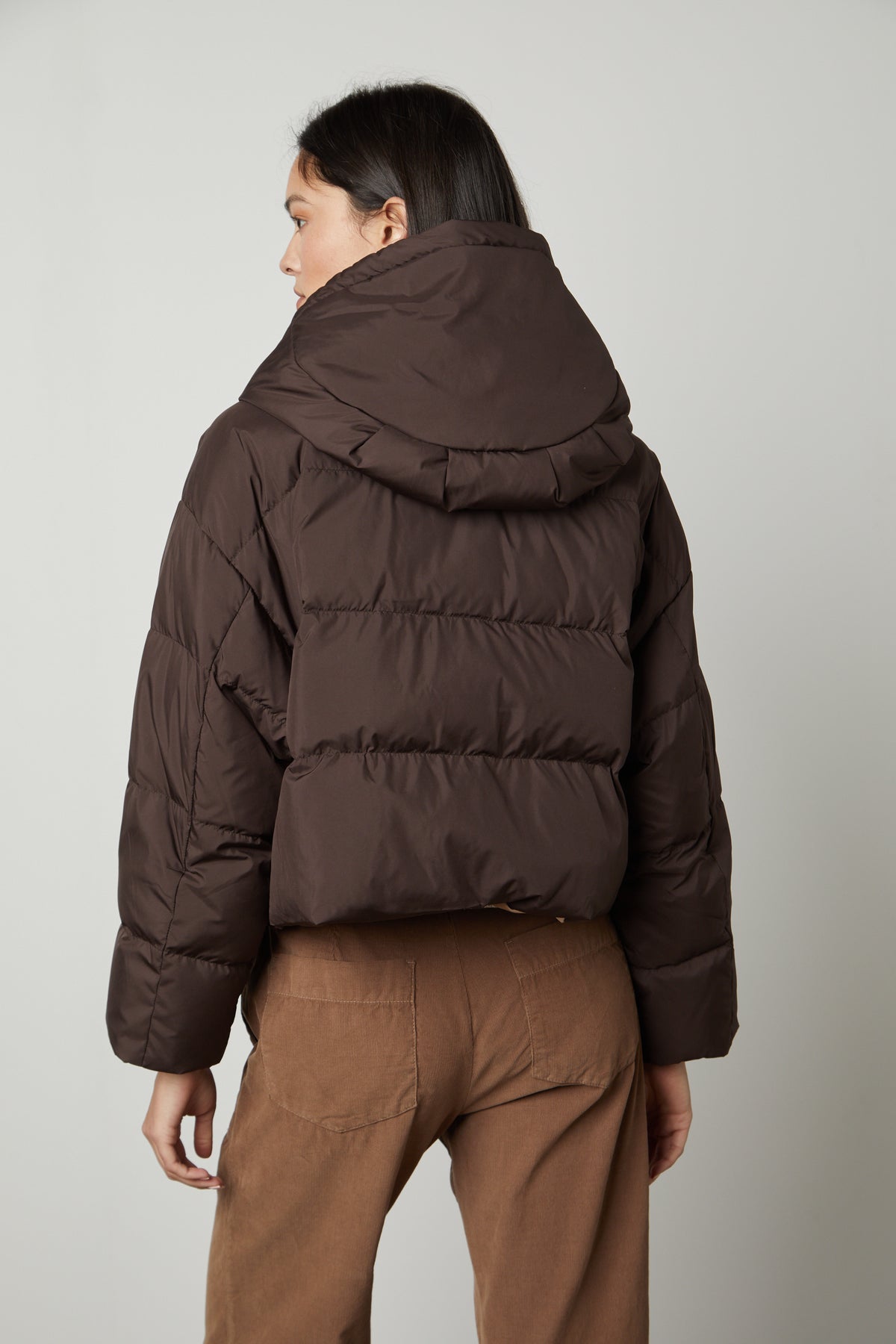The back view of a woman wearing a Velvet by Graham & Spencer RAYLIN CROPPED PUFFER JACKET.