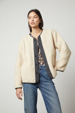 The model is wearing a cozy Velvet by Graham & Spencer Marissa Reversible Quilted Sherpa Jacket and jeans.