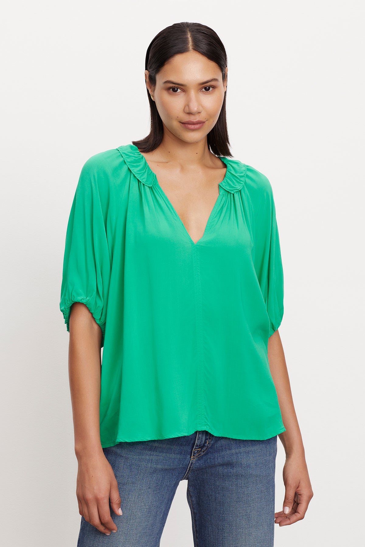 The model is wearing a green Velvet by Graham & Spencer ALEGRA V-NECK TOP.