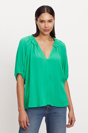 The model is wearing a green Velvet by Graham & Spencer ALEGRA V-NECK TOP.