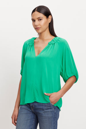 A model wearing a Velvet by Graham & Spencer ALEGRA V-NECK TOP with puff sleeves.