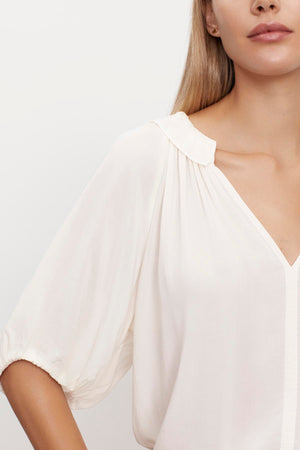 The model is wearing a white ALEGRA V-NECK TOP by Velvet by Graham & Spencer with puff sleeves.