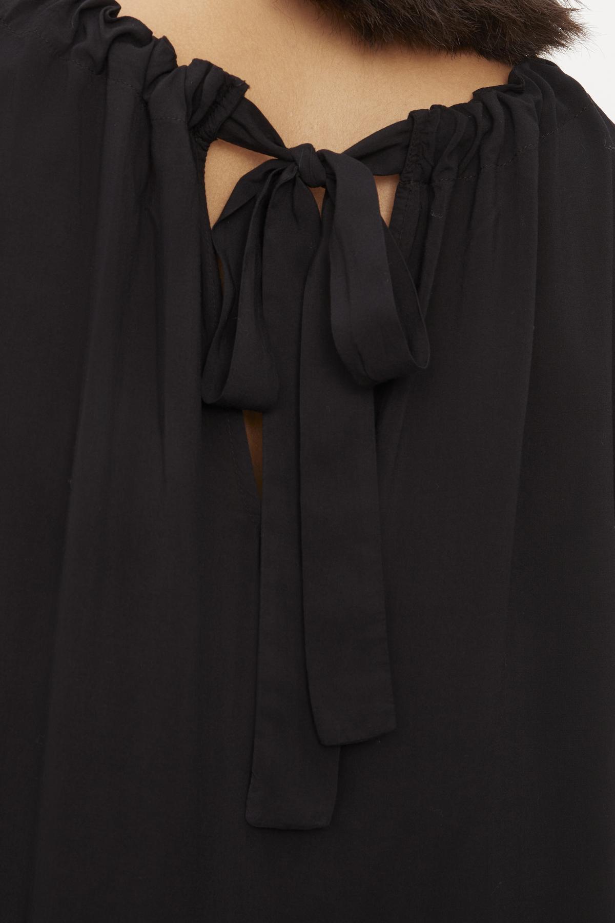 The back of a woman's black Bristol Neck Tie Top with a luxurious bow and tie closure by Velvet by Graham & Spencer.-36001351205057