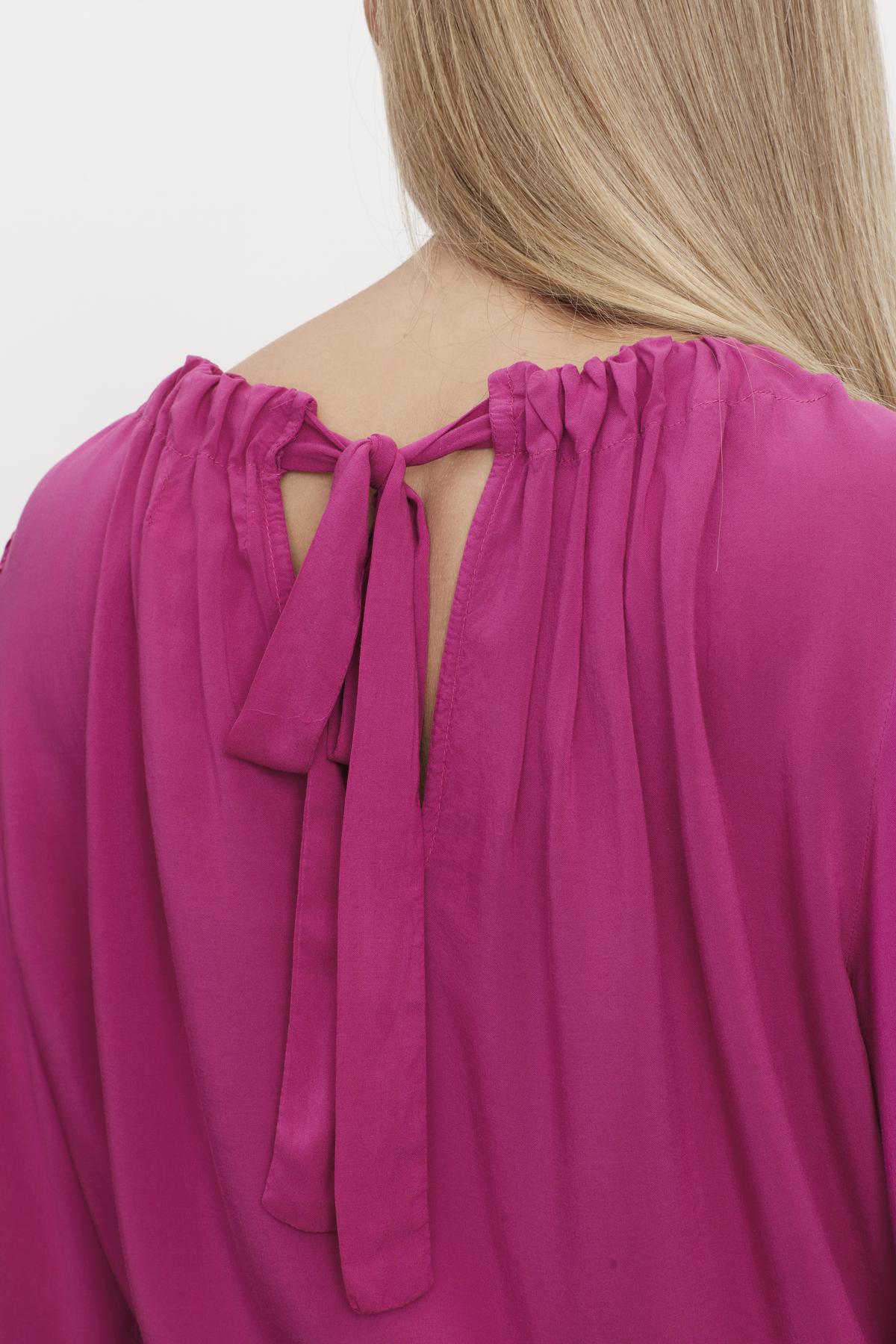 The back view of a woman wearing a Velvet by Graham & Spencer BRISTOL NECK TIE TOP featuring a tie closure.-35655627604161