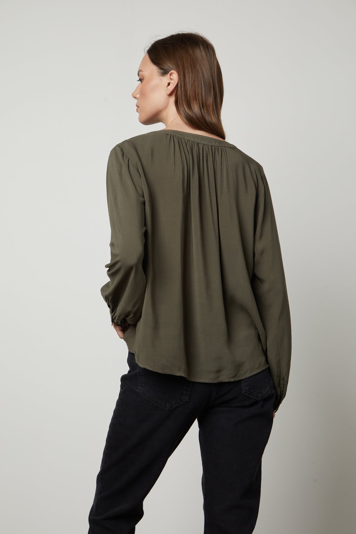 The back view of a woman wearing jeans and a Velvet by Graham & Spencer POSIE SPLIT NECK BLOUSE.-26834994331841