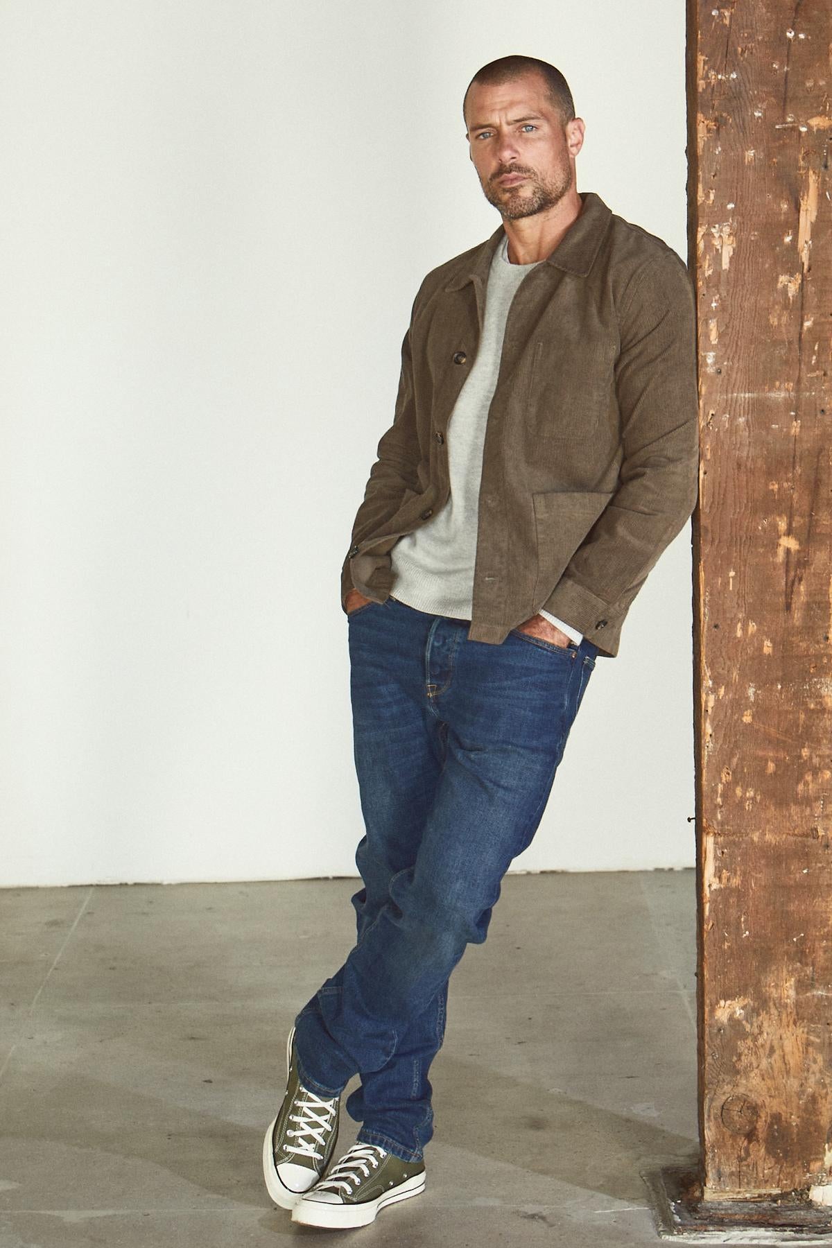 A man leaning against a wall in a REIKO corduroy chore jacket by Velvet by Graham & Spencer.-26846359290049
