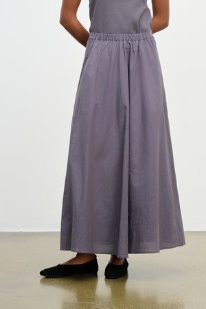 A person wearing the FILLA SKIRT by Velvet by Graham & Spencer, styled with black flats and a sleeveless gray top, stands against a plain background.