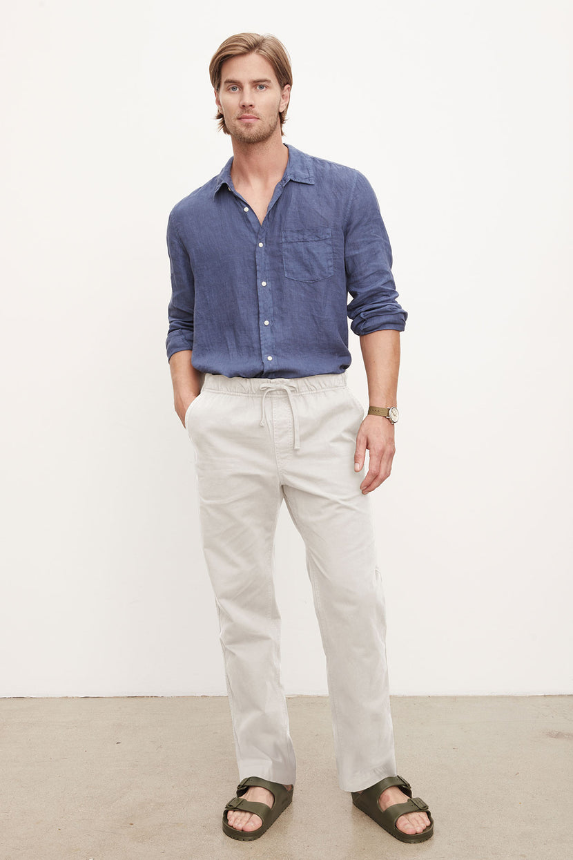 A man in a casual blue shirt and Velvet by Graham & Spencer BRANSON PANT, standing against a plain background.