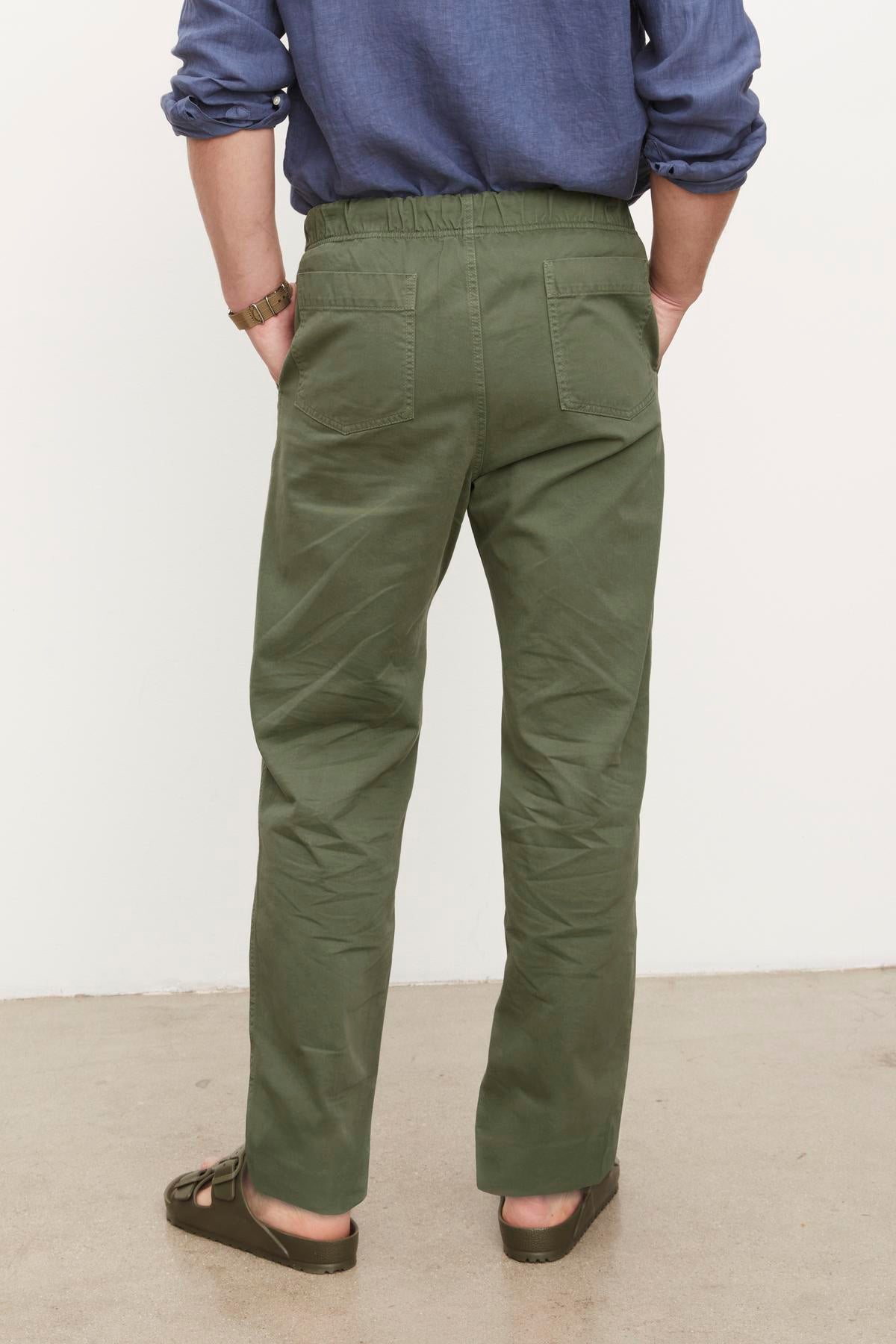 A person wearing Velvet by Graham & Spencer's Branson Pant with an elastic drawstring waist and brown shoes viewed from behind.-36329591210177