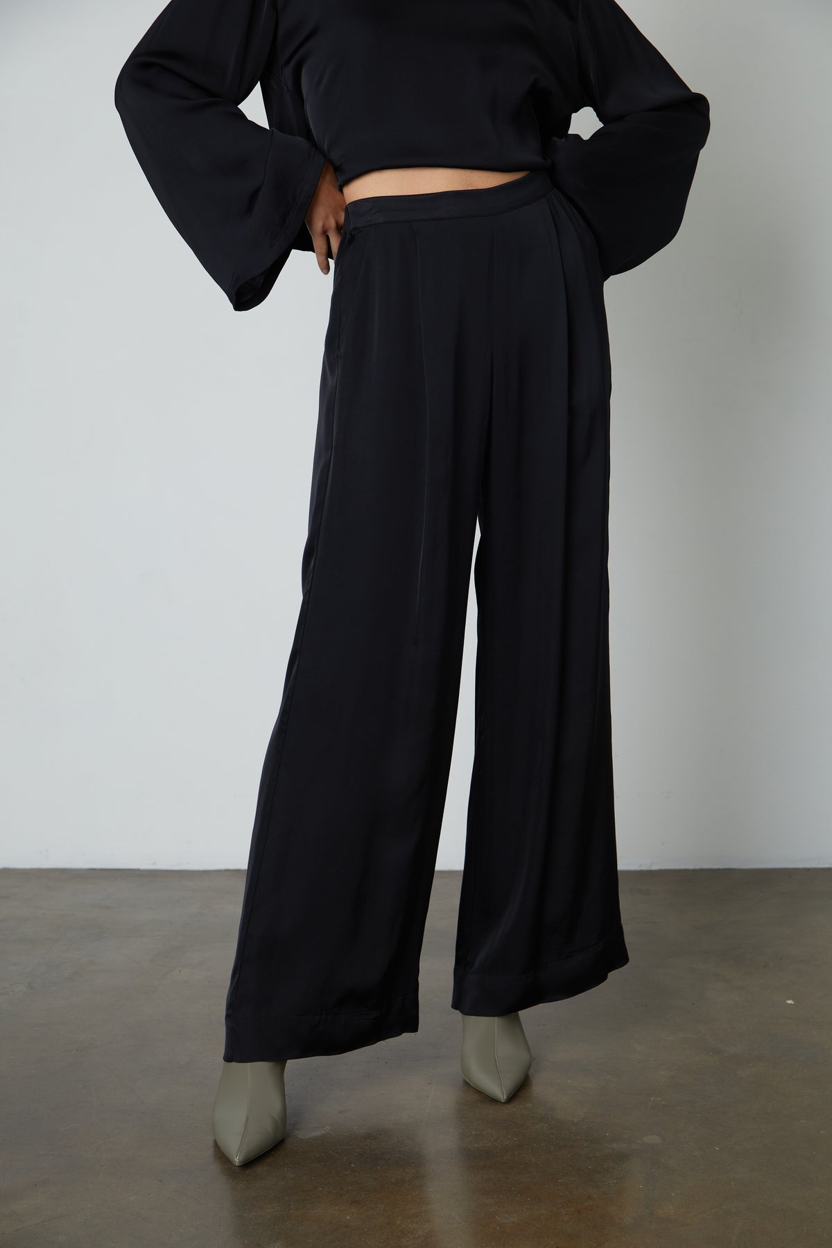 A model wearing Velvet by Graham & Spencer LIVI SATIN VISCOSE WIDE LEG PANT with an elastic waistline and slash pockets.-35656282177729