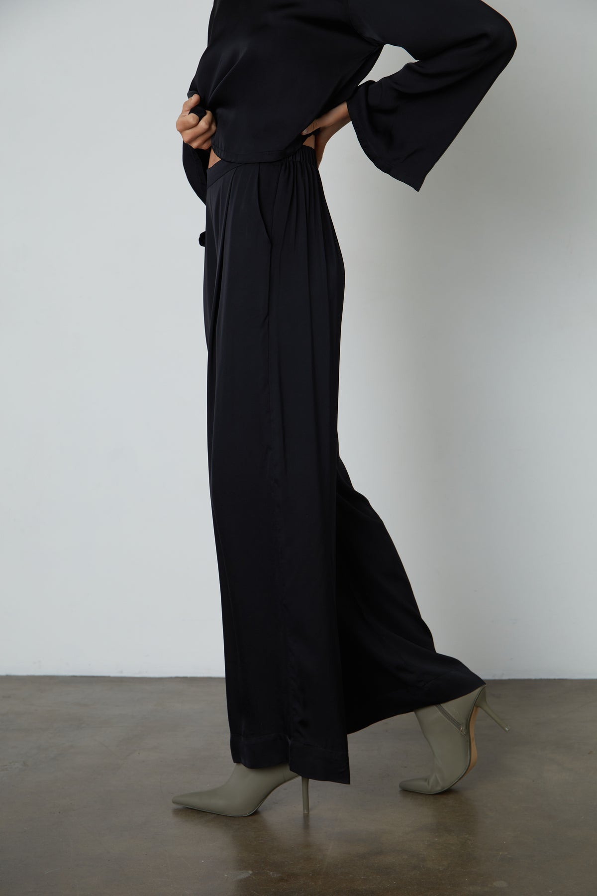 The model is wearing Velvet by Graham & Spencer's LIVI SATIN VISCOSE WIDE LEG PANT with slash pockets and an elastic waistline.-35656282210497
