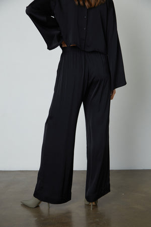 The back view of a woman wearing Velvet by Graham & Spencer LIVI SATIN VISCOSE WIDE LEG PANT with slash pockets.
