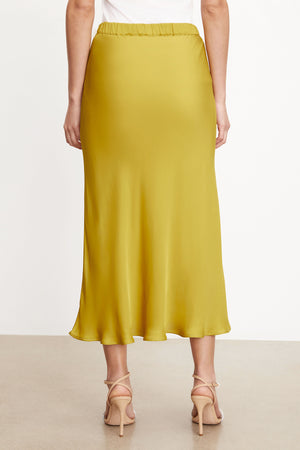 The silhouette of a woman wearing a AUBREE SATIN MIDI SKIRT from Velvet by Graham & Spencer showcases its satin woven fabric.