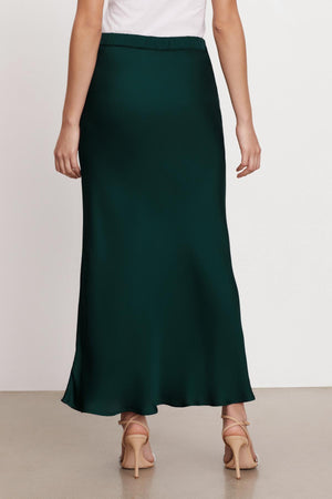 The back view of a woman wearing a Velvet by Graham & Spencer CADENCE SATIN MAXI SKIRT with a flattering fit.