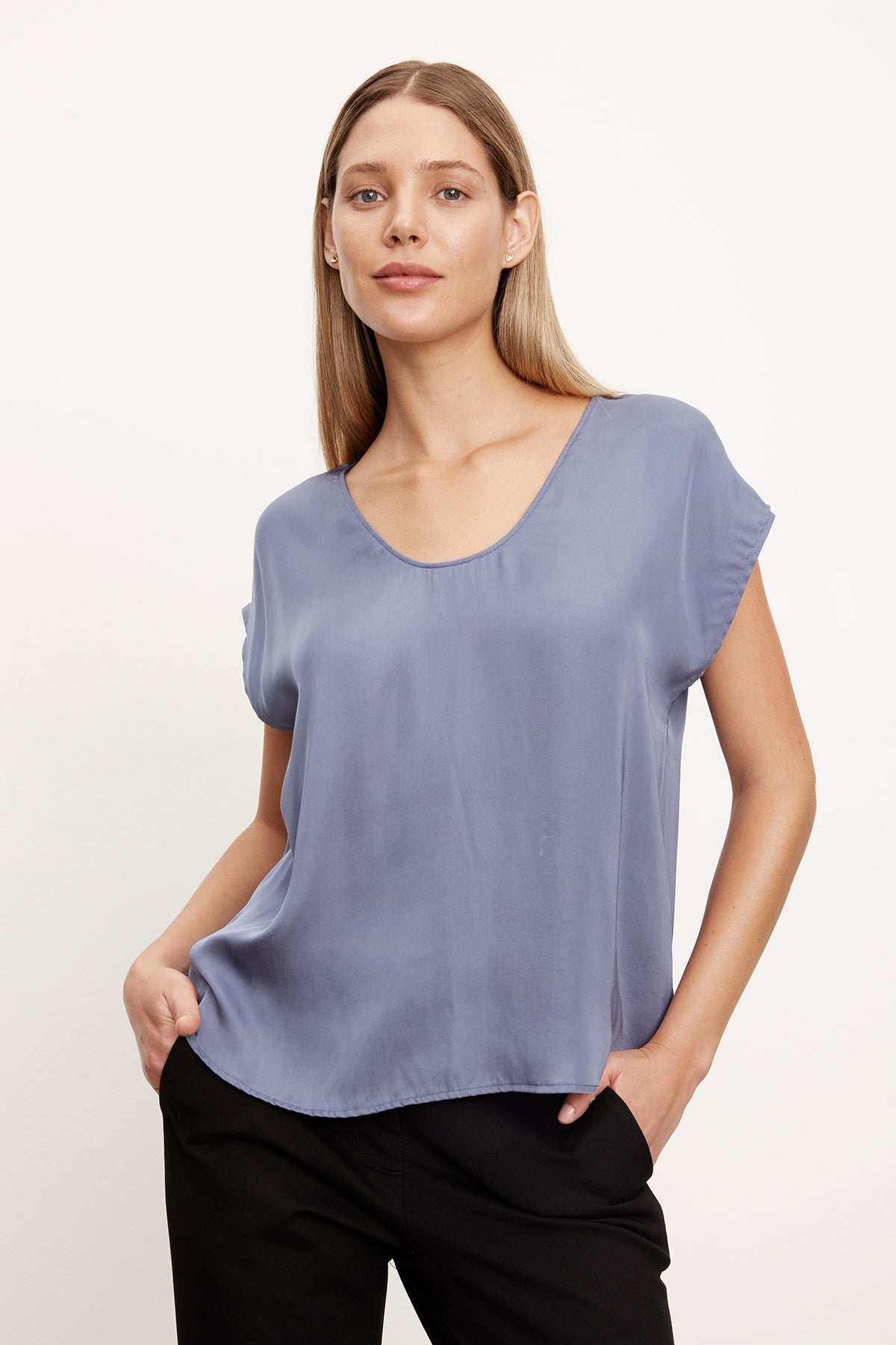 The model is wearing a Velvet by Graham & Spencer KALI SATIN SCOOP NECK TOP in blue.-35577759727809