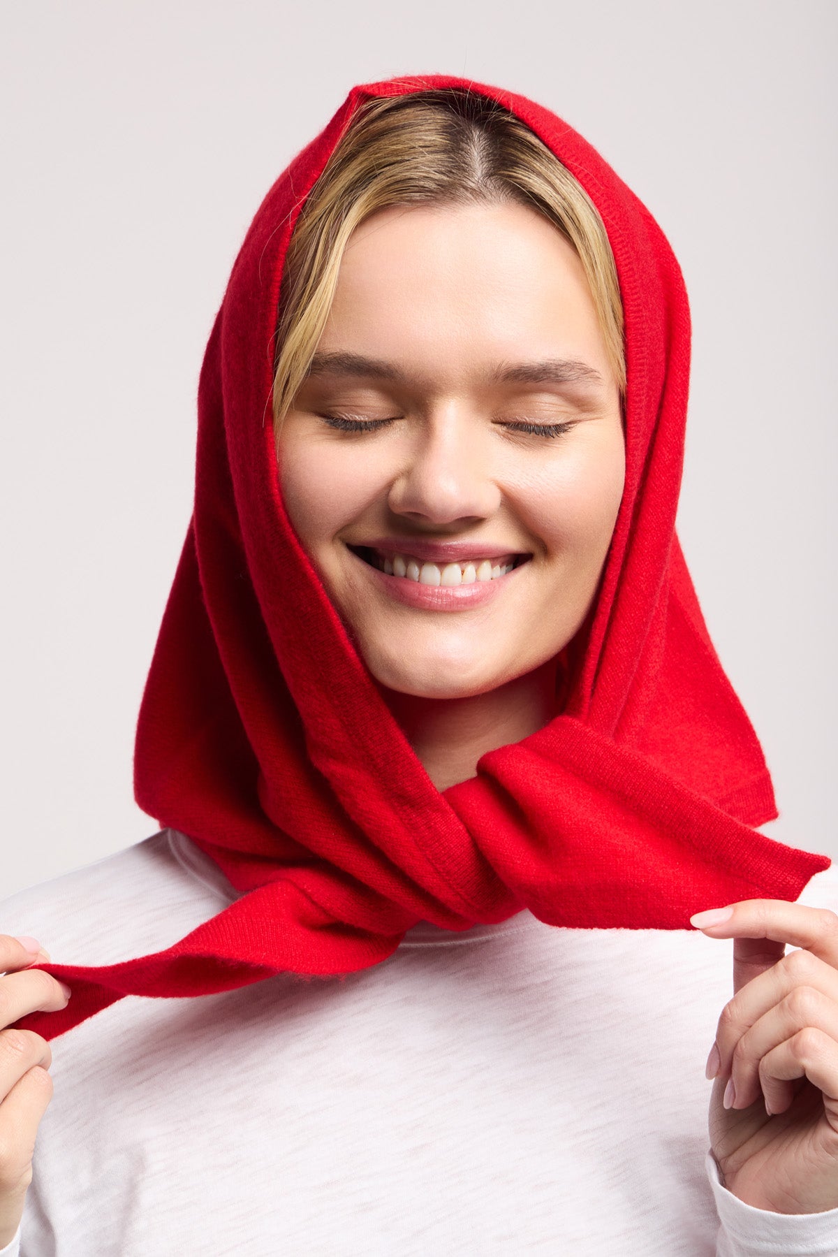 A woman with closed eyes and a smile wears the LARGE TRIANGLE BANDANA BY 40 COLORI over her head, holding the ends of this bold Italian accessory by 40 Colori in her hands.-40459576443073