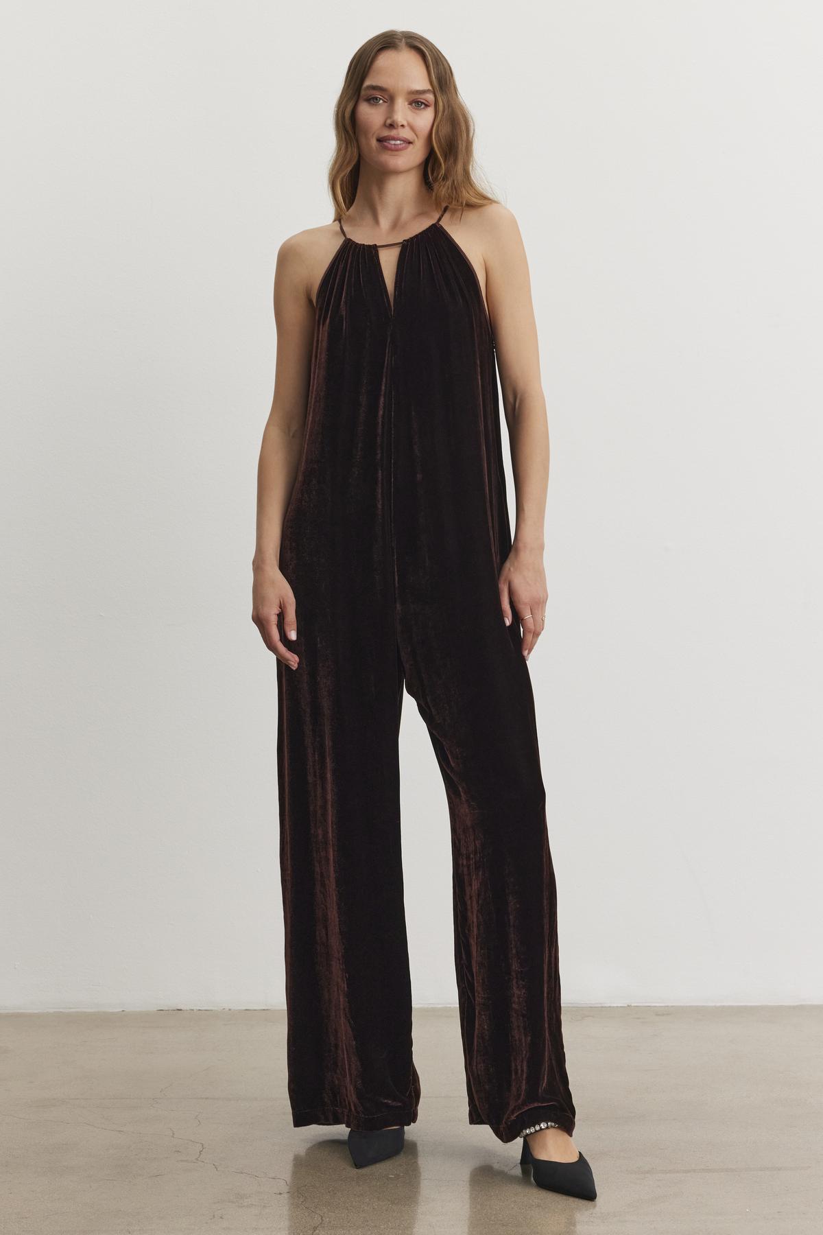 An individual wearing the CIENNA SILK VELVET JUMPSUIT from Velvet by Graham & Spencer, paired with black shoes, stands against a white background.-38246397247681