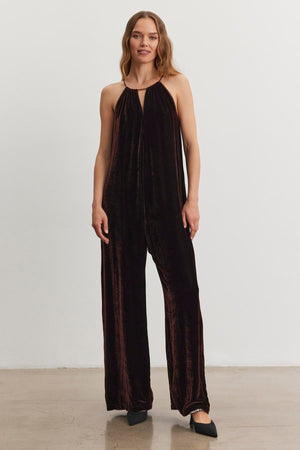 An individual wearing the CIENNA SILK VELVET JUMPSUIT from Velvet by Graham & Spencer, paired with black shoes, stands against a white background.