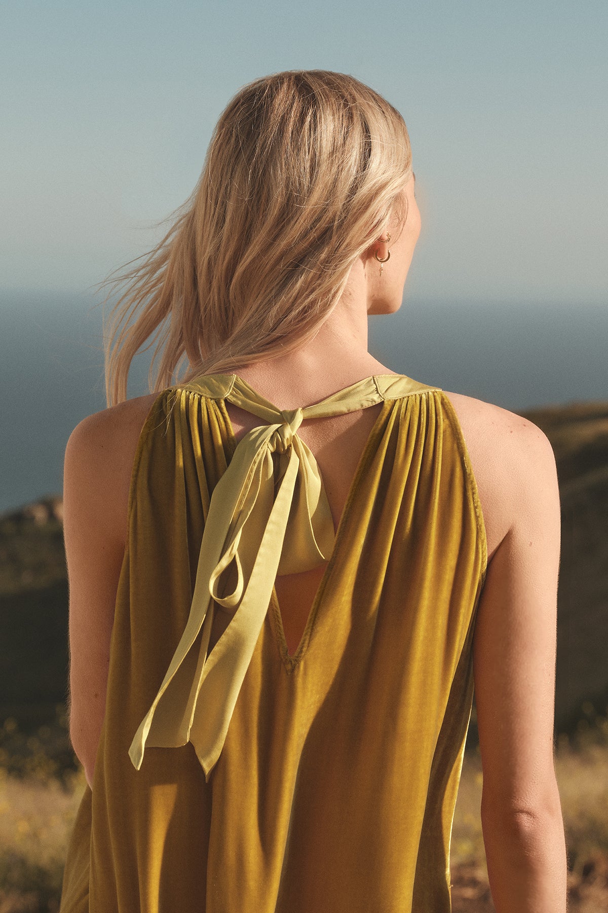 A woman in a MAREN SILK VELVET HALTER DRESS by Velvet by Graham & Spencer looking out over the ocean.-35571948912833