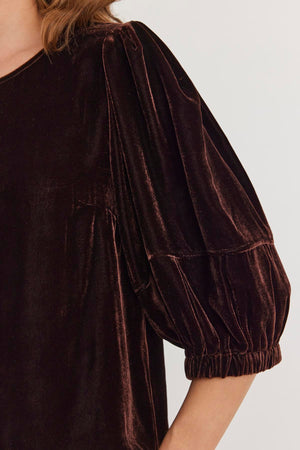 Close-up of someone wearing the NANCY SILK VELVET TOP by Velvet by Graham & Spencer, featuring puffed sleeves, a shirred shoulder, and gathered cuffs.