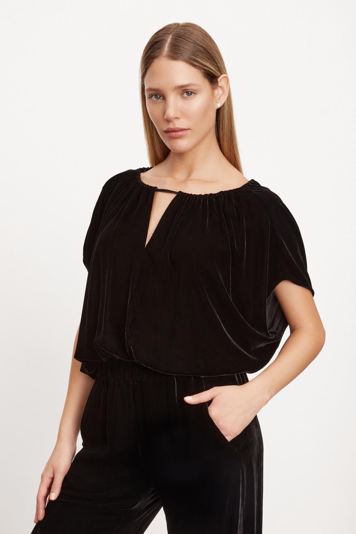 The model is wearing a NOA SILK VELVET CROPPED TOP by Velvet by Graham & Spencer, black velvet jumpsuit with adjustable tie and V-neck top.-35654468796609