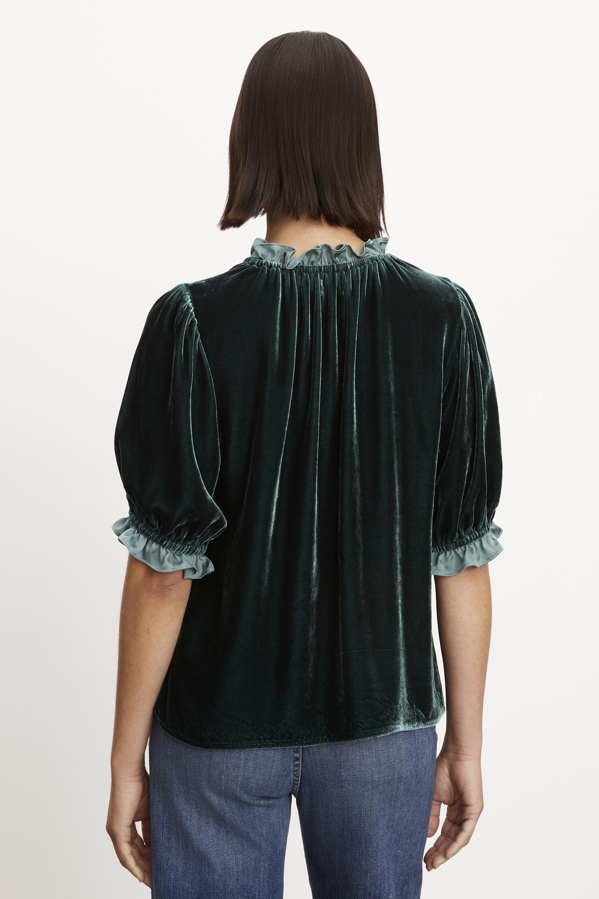 The back view of a woman wearing a Velvet by Graham & Spencer VAL SILK VELVET TOP with elastic ruffle neckline.
