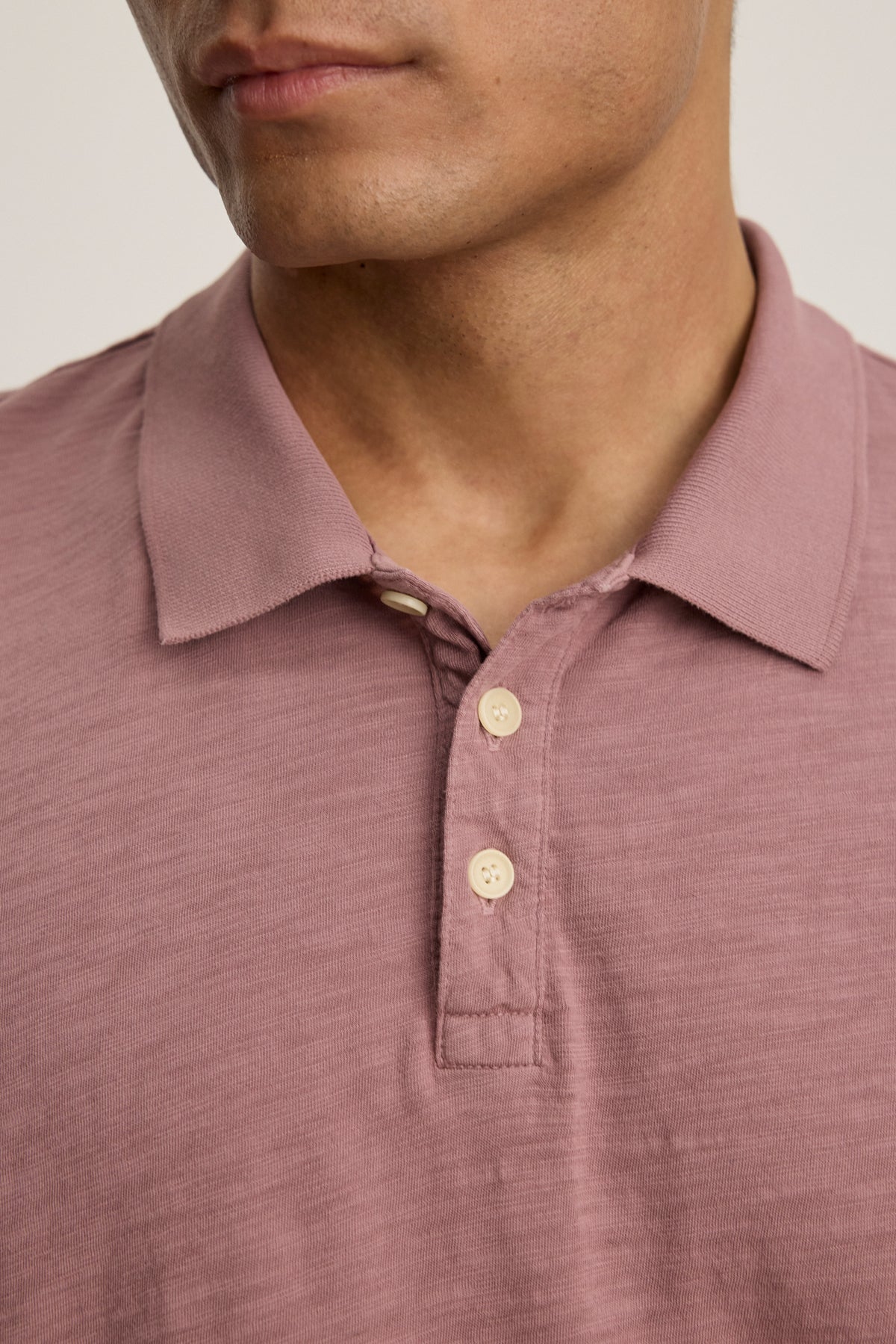 A person wearing the NIKO POLO by Velvet by Graham & Spencer, a mauve short-sleeve Peruvian cotton polo with three buttons, shown from the shoulders to just above the lips.-40054347235521