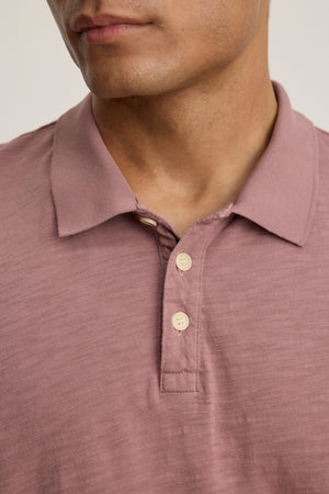 A person wearing the NIKO POLO by Velvet by Graham & Spencer, a mauve short-sleeve Peruvian cotton polo with three buttons, shown from the shoulders to just above the lips.