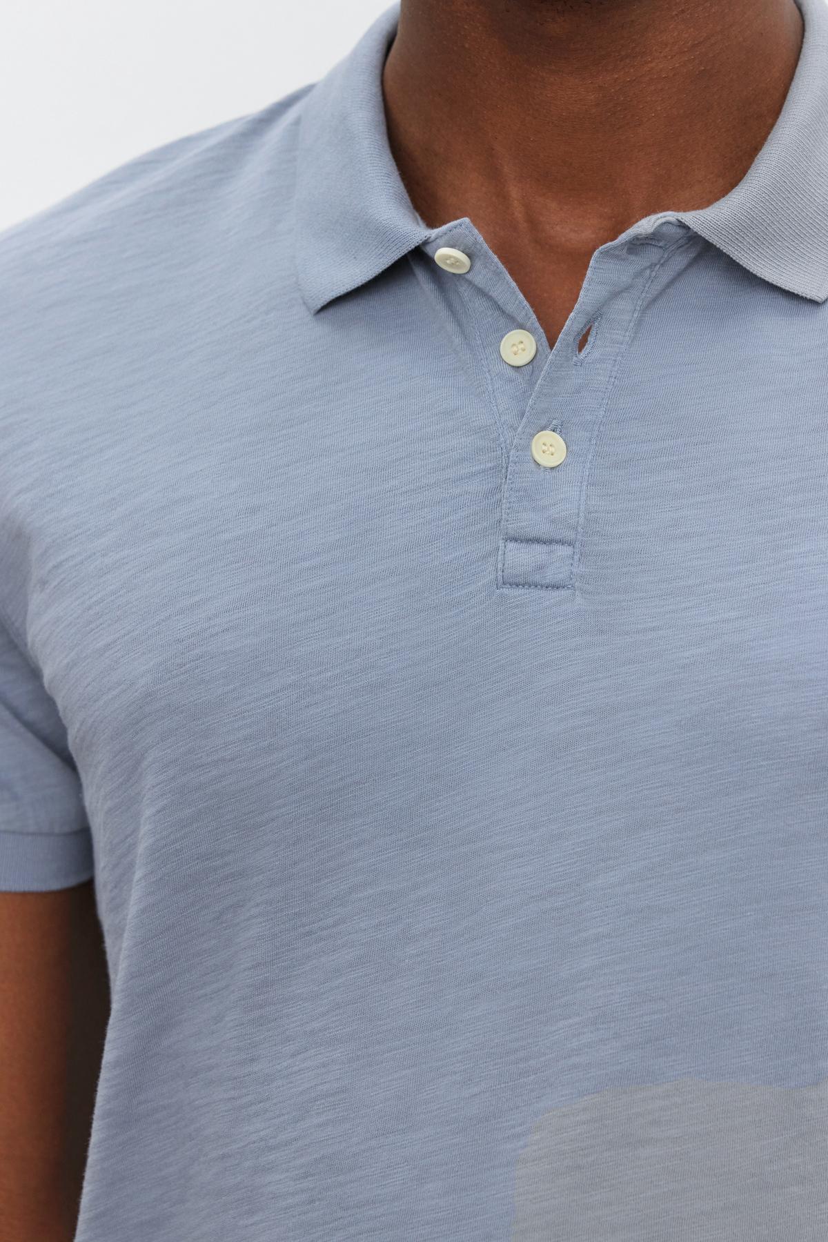 A person wears a light blue short-sleeve, classic NIKO POLO shirt by Velvet by Graham & Spencer with three buttons, captured from the chest up against a plain background. The cotton slub fabric gives it a subtle vintage feel.-37469125836993