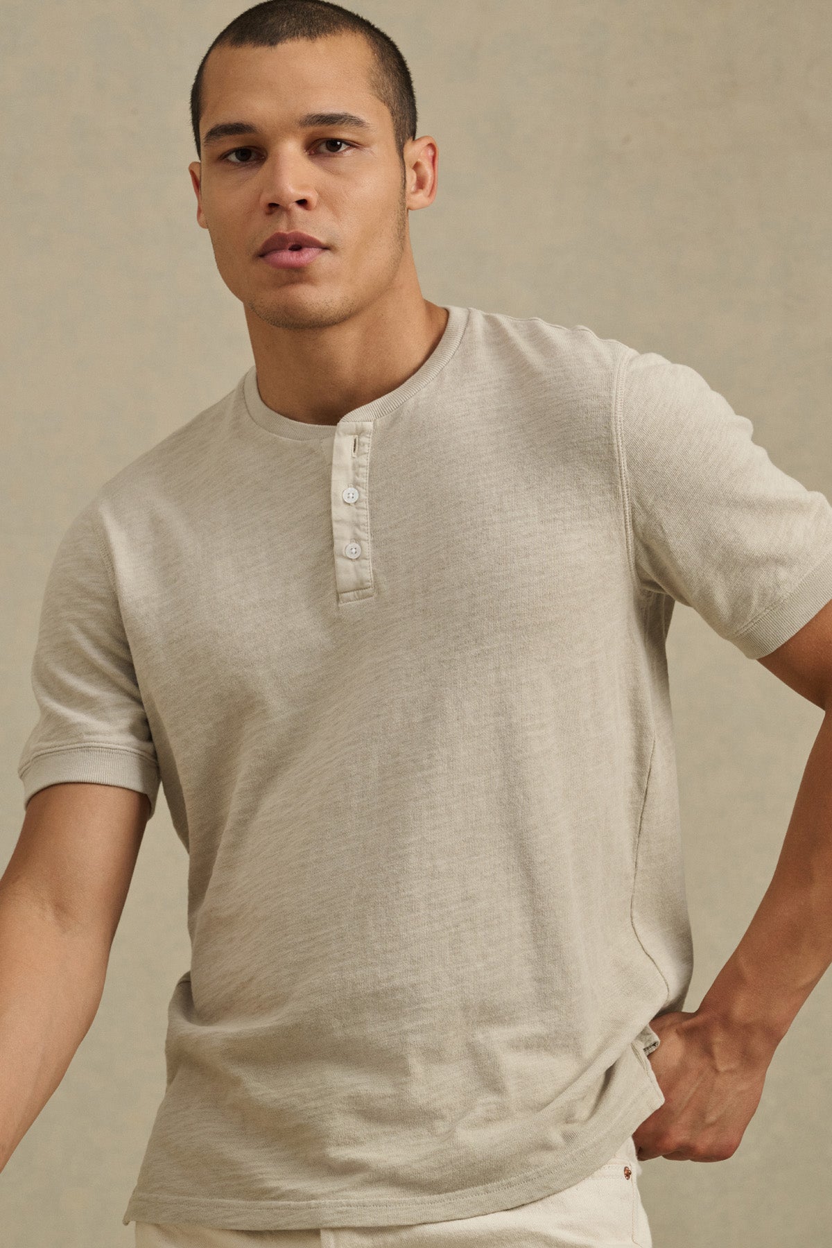 A person models the JENKINS HENLEY by Velvet by Graham & Spencer in light beige cotton, standing against a plain background to showcase effortless casual style.-41104761225409