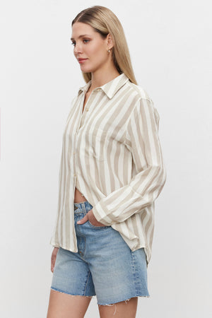 The model is wearing striped shorts and a Velvet by Graham & Spencer HARLOW STRIPED LINEN BUTTON-UP SHIRT.