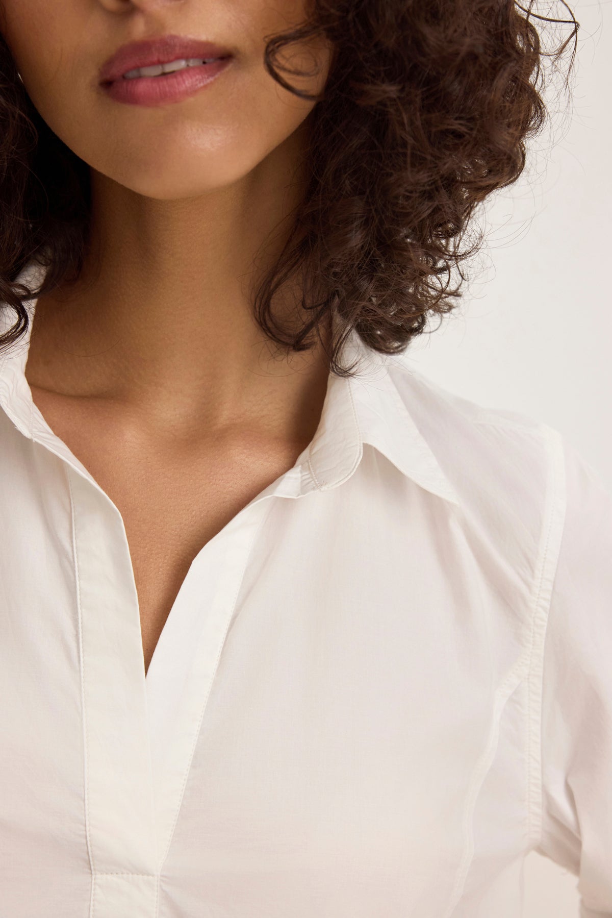 A person with curly hair is partially visible, wearing a MISSIE DRESS by Velvet by Graham & Spencer, focusing on the dress's white button-up detail and the shoulders.-38820784144577
