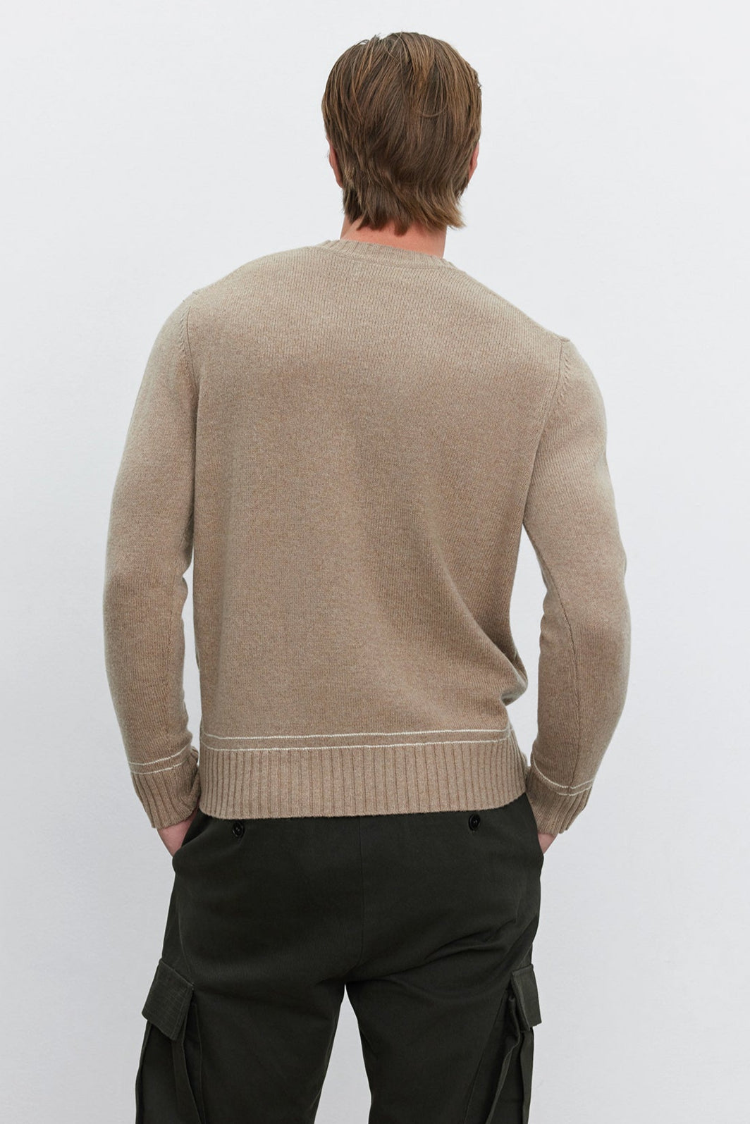 A person with brown hair is seen from the back, wearing the ATTICUS SWEATER by Velvet by Graham & Spencer in a beige wool blend and dark green cargo pants.-37893828411585