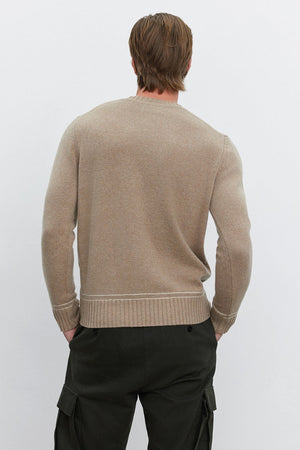 A person with brown hair is seen from the back, wearing the ATTICUS SWEATER by Velvet by Graham & Spencer in a beige wool blend and dark green cargo pants.