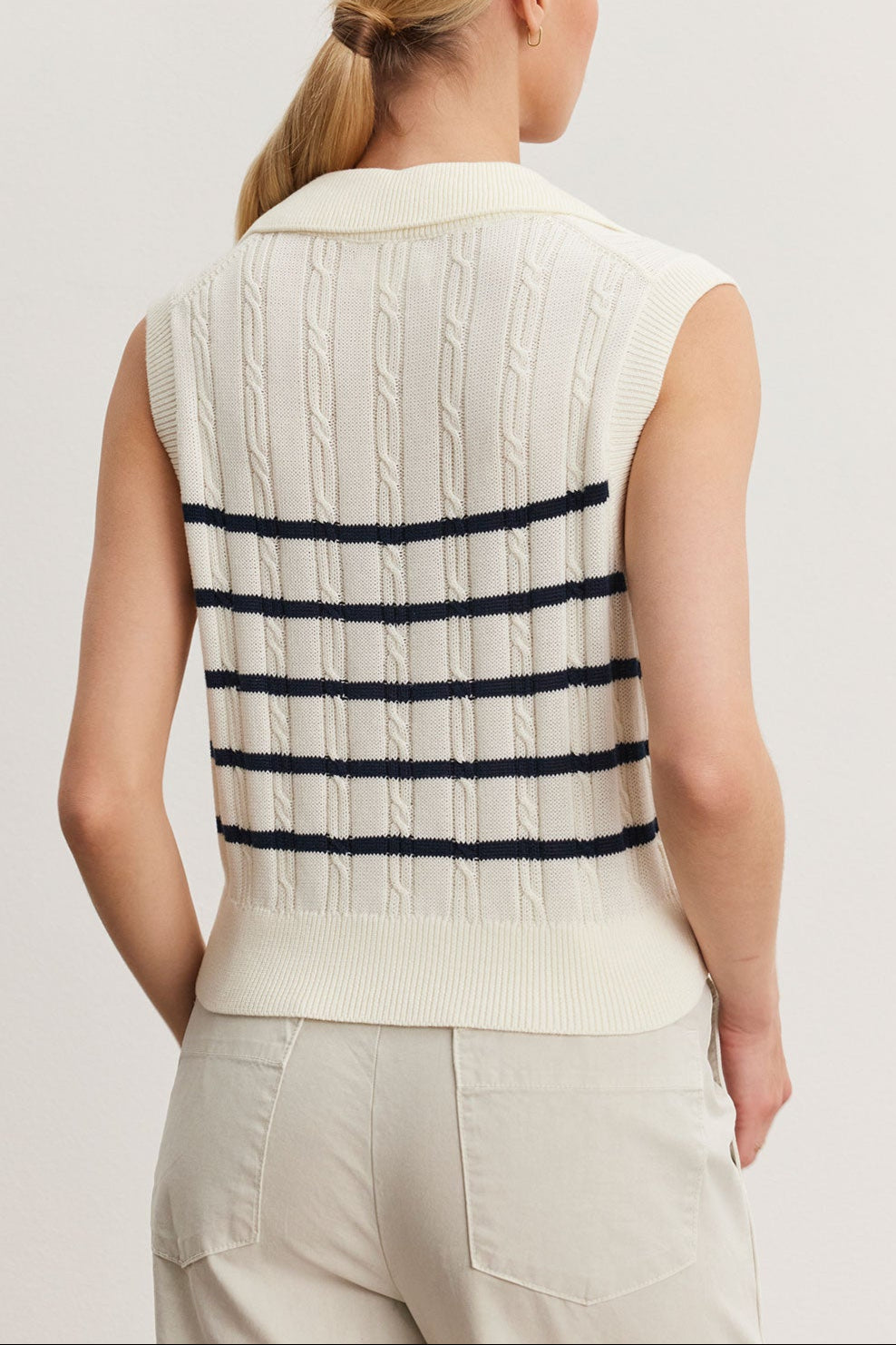 Woman viewed from behind, wearing a white Velvet by Graham & Spencer WENDY SWEATER VEST with horizontal black stripes, paired with beige pants.-36998737985729
