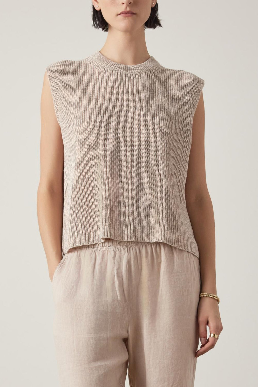 A person with short dark hair is wearing the Velvet by Jenny Graham's GARDENA LINEN SWEATER VEST and light brown relaxed fit pants, standing against a plain background.-37628705964225