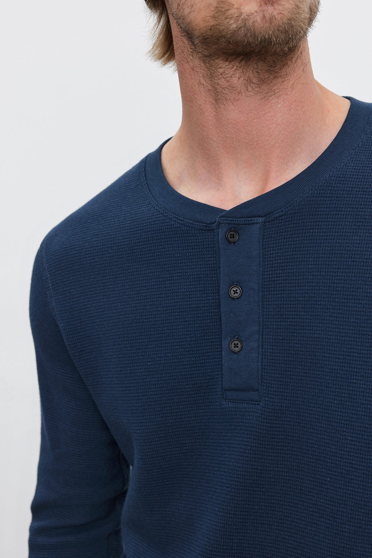 A man wears the DEX THERMAL HENLEY by Velvet by Graham & Spencer, a blue, long-sleeve henley shirt featuring a 3-button placket. He is shown from the shoulders to just above the nose. The cotton thermal knit makes it perfect for layering.-37893766611137