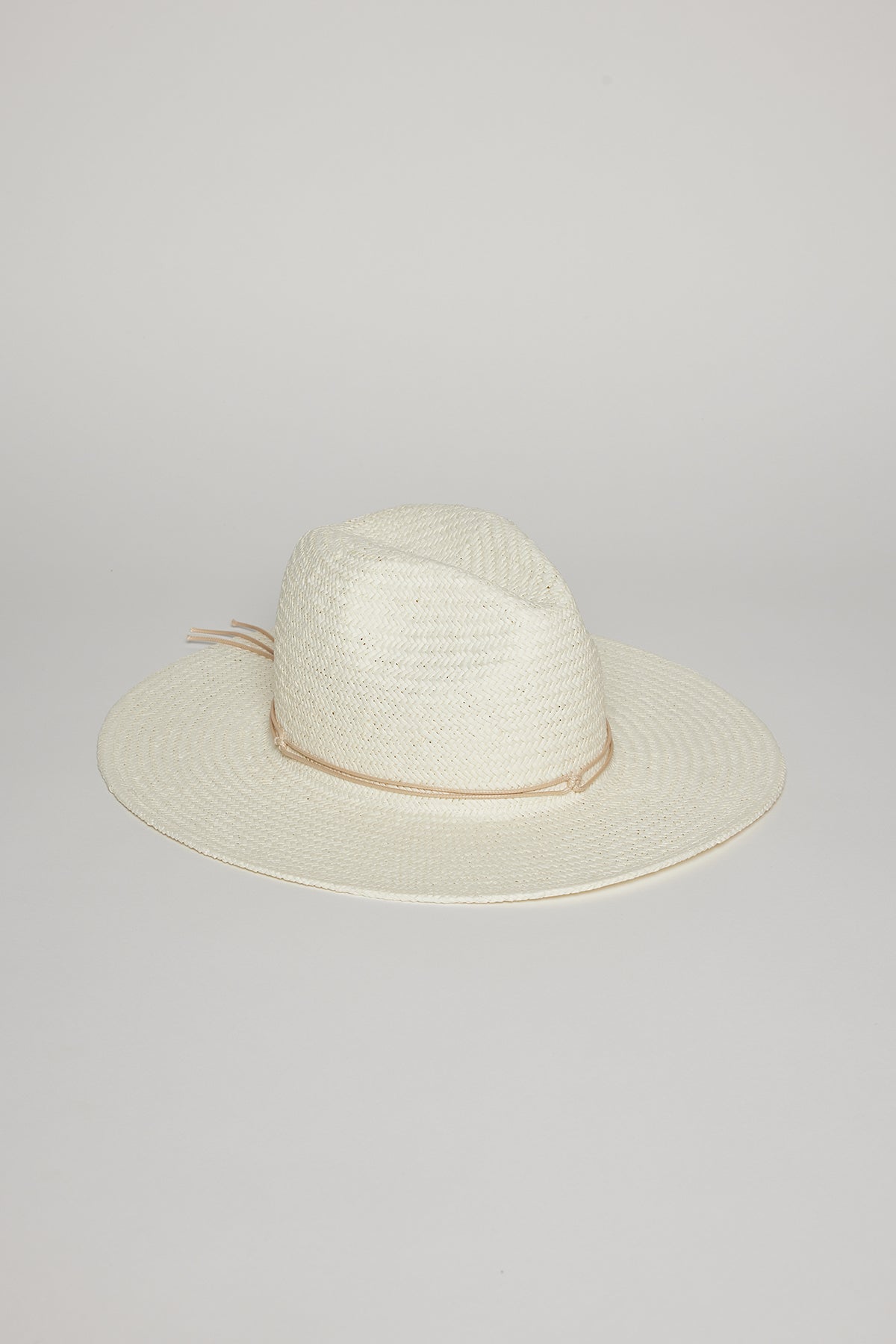 A white, wide-brimmed TRAVELER CONTINENTAL HAT by Velvet by Graham & Spencer with a beige band around the base of the crown, placed on a light grey surface.-36290936078529