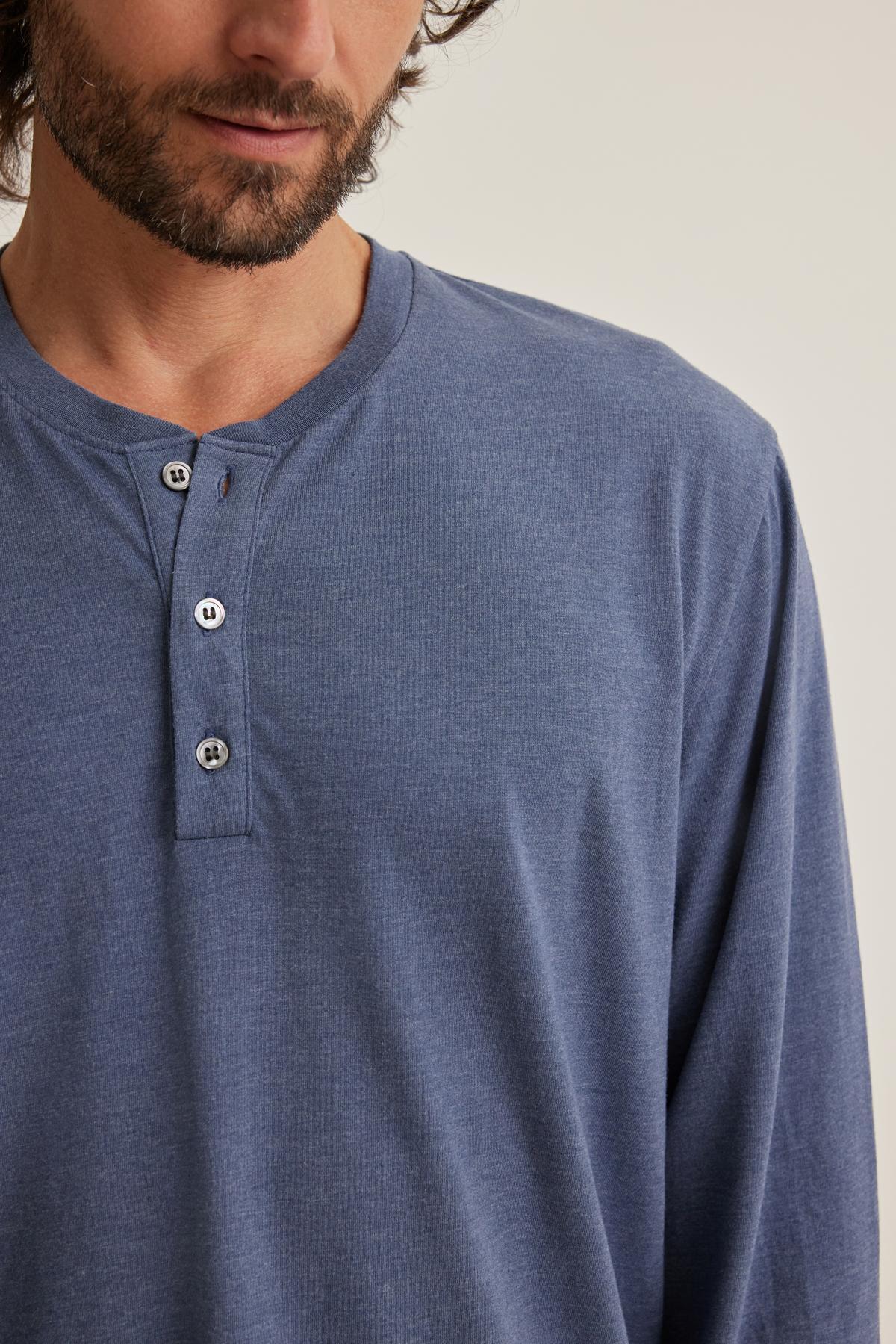 Man in a Velvet by Graham & Spencer DESI HENLEY shirt, blue with button details, looking slightly downwards.