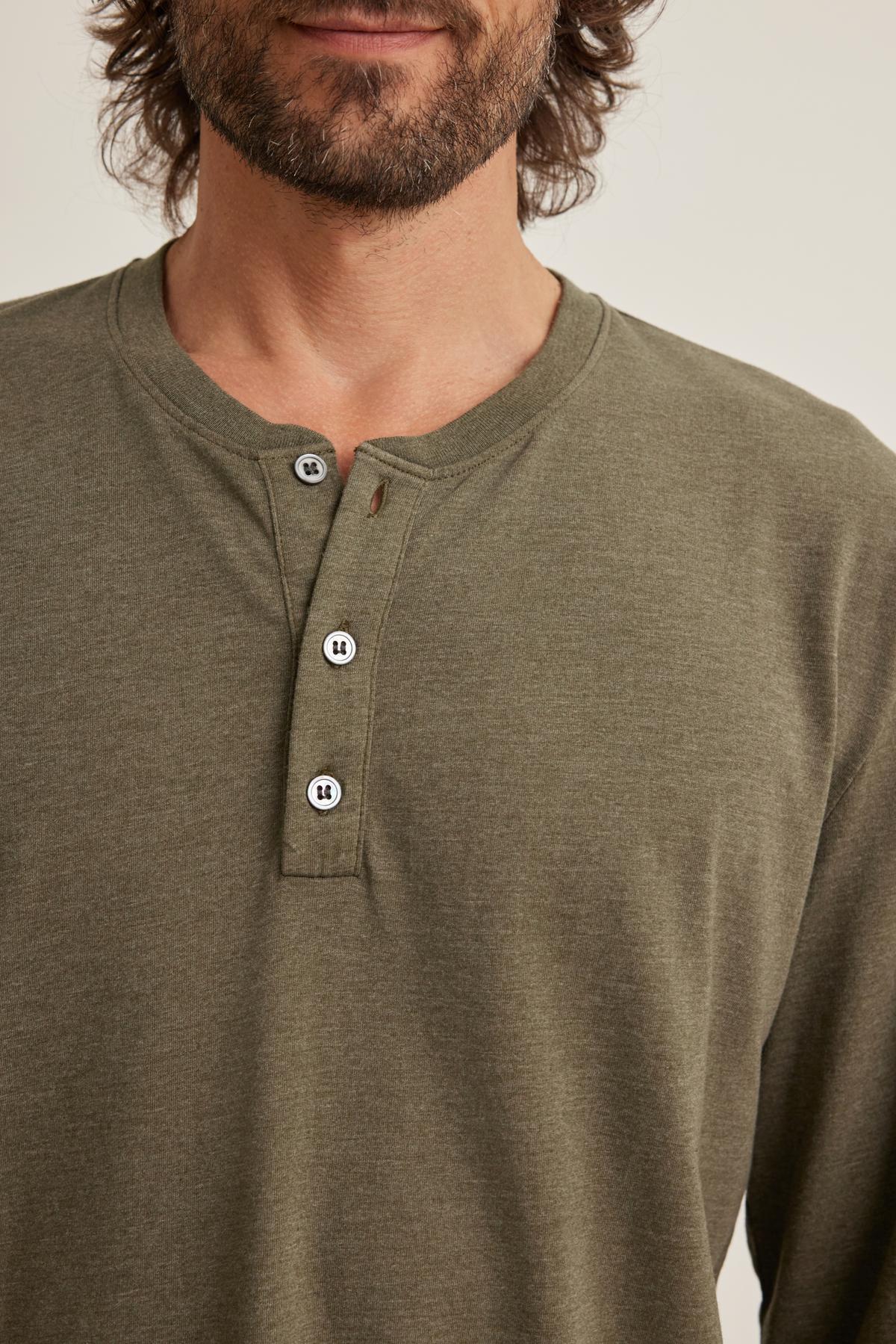A person wearing the Velvet by Graham & Spencer DESI HENLEY in green, featuring three visible buttons, stands against a plain background.
