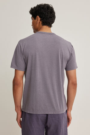 A person stands facing away from the camera, wearing the relaxed-fit ZANDER TEE by Velvet by Graham & Spencer— a short-sleeved gray top in a cotton-modal blend—paired with matching shorts, set against a plain background.