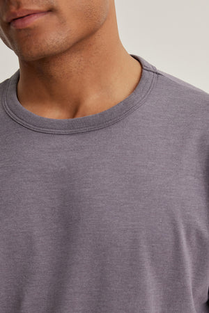 A close-up of a person wearing the ZANDER TEE by Velvet by Graham & Spencer, a plain gray crew neck t-shirt made from a soft cotton-modal blend, shown from shoulders to chin for everyday comfort.