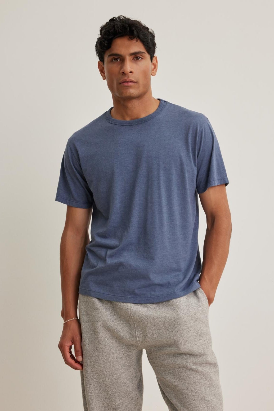 A person is wearing the ZANDER TEE by Velvet by Graham & Spencer paired with gray pants, standing against a plain background.