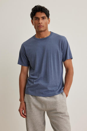 A person is wearing the ZANDER TEE by Velvet by Graham & Spencer paired with gray pants, standing against a plain background.