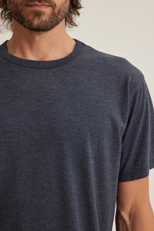 A man with a beard wears the ZANDER TEE by Velvet by Graham & Spencer, a dark gray cotton-modal short-sleeve shirt, shown from shoulders to mid-chest against a plain background.