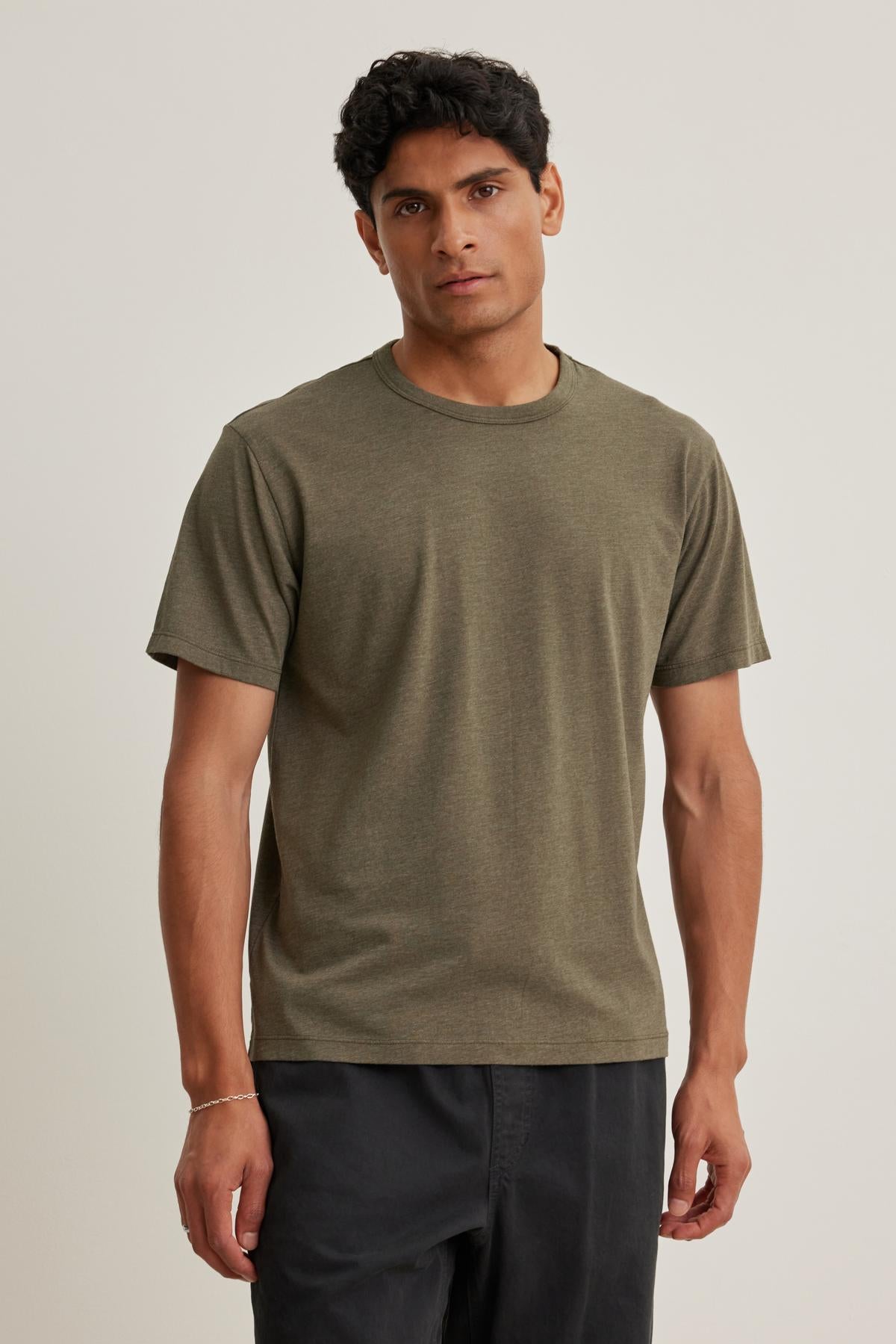A person wearing a ZANDER TEE by Velvet by Graham & Spencer and dark pants stands against a plain background.
