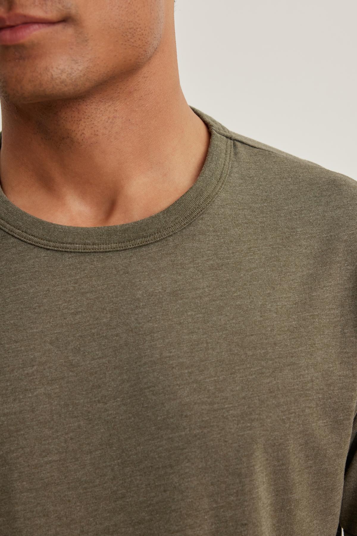 Close-up of a person in a ZANDER TEE by Velvet by Graham & Spencer, showing part of the jawline and neck against a neutral background.