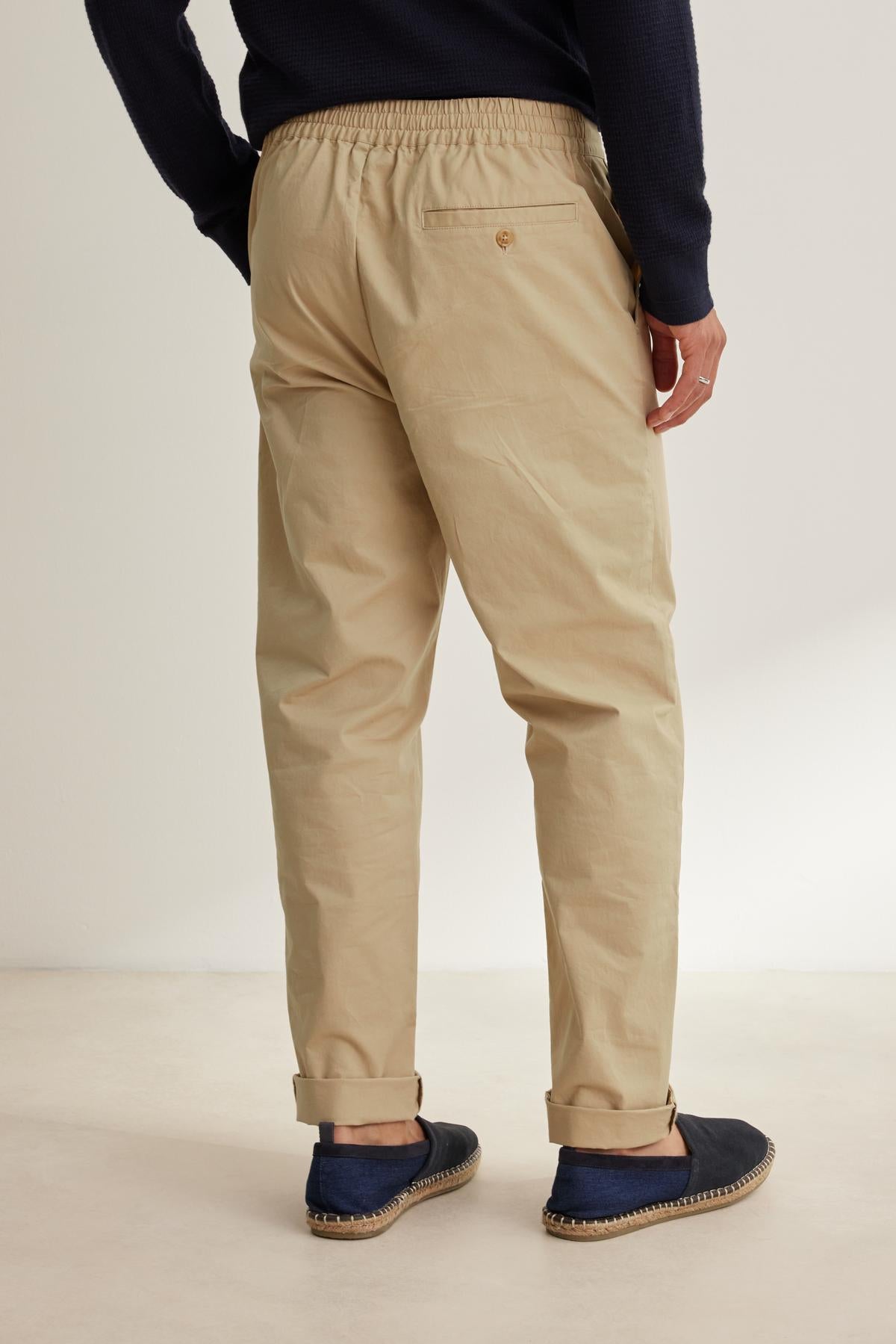 A person is standing in a neutral-toned room wearing a dark sweatshirt, STONE PANT from Velvet by Graham & Spencer, and navy espadrilles, facing away.-38643359449281