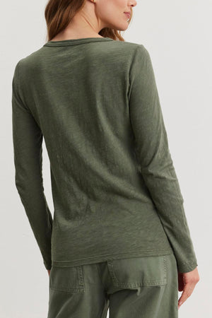 A person with long hair is wearing Velvet by Graham & Spencer's LIZZIE TEE, an olive green cotton slub top, along with pants. The outfit features a subtle crew neckline as they face away.