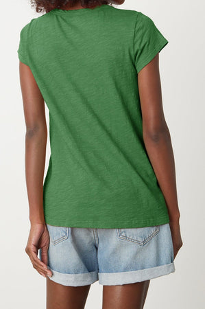 A person is shown from the back wearing a green KIRA TEE by Velvet by Graham & Spencer with a scoop neckline and denim shorts with rolled hems, perfect for everyday wear.